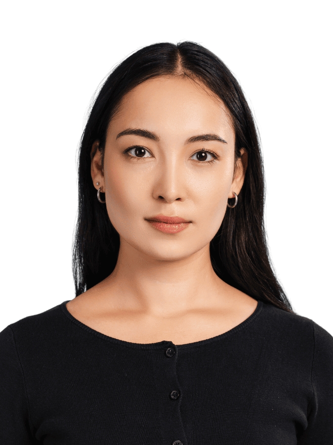 A person with long hair and hoop earrings looks directly at the camera, wearing a dark top, with a plain black background.