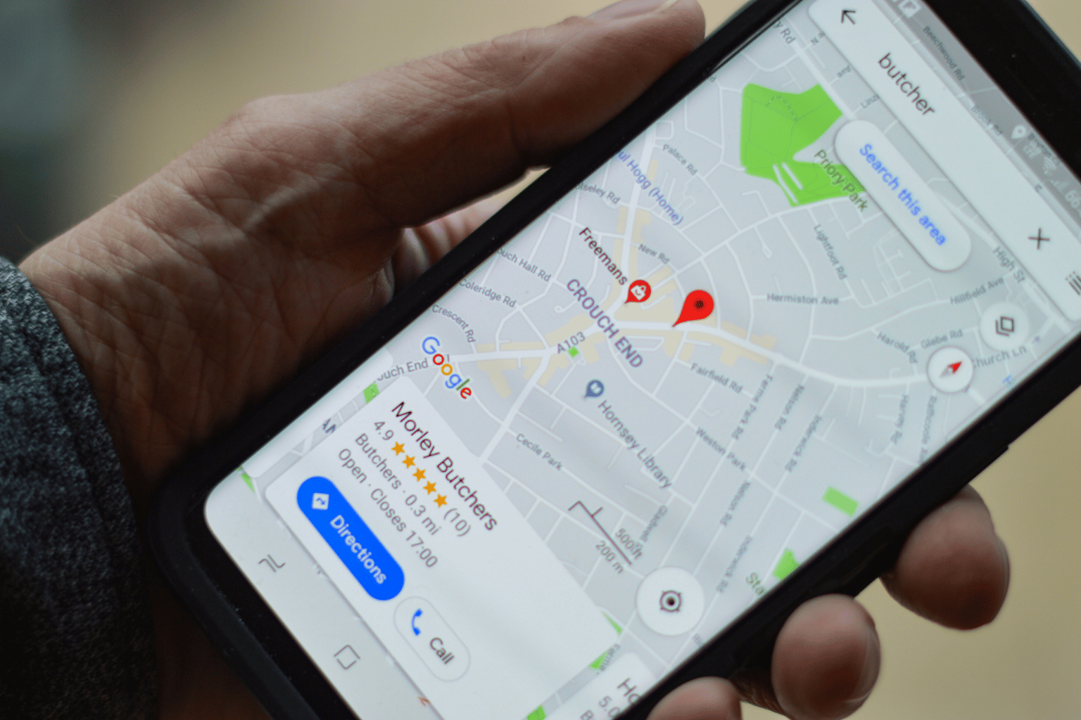 Map Pins on Phone Screen A hand holding a smartphone displaying a map with red location pins.